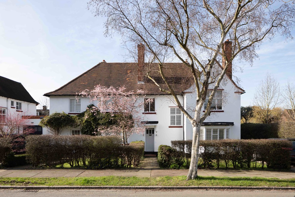 Mid-sized country three-storey stucco white duplex exterior in London.