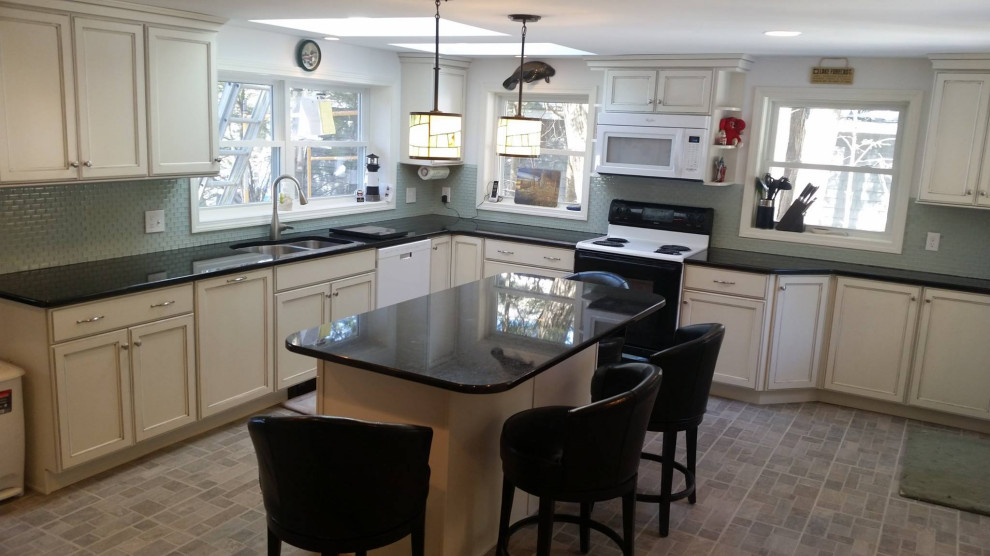 This is an example of a large transitional l-shaped kitchen pantry in Manchester with a double-bowl sink, shaker cabinets, white cabinets, granite benchtops, green splashback, porcelain splashback, stainless steel appliances, vinyl floors, with island, grey floor, black benchtop and recessed.