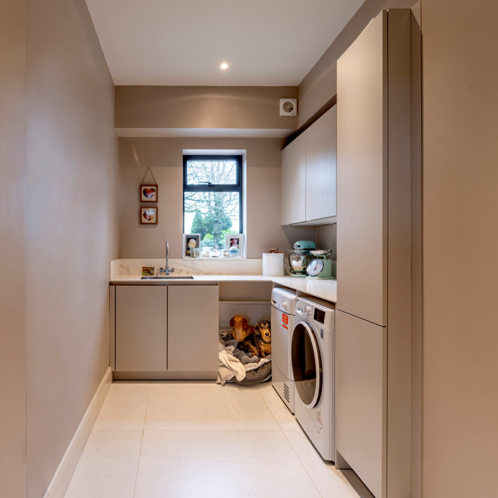 Inspiration for a large contemporary l-shaped laundry room in Cheshire with flat-panel cabinets, tile benchtops, porcelain floors, grey floor, black benchtop and coffered.