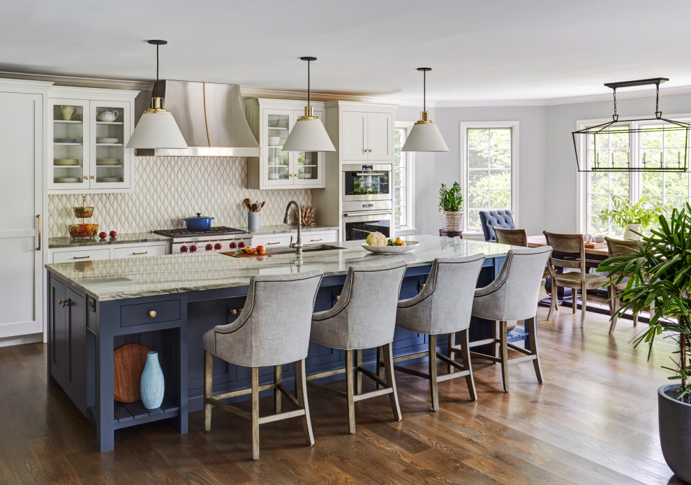 Example of a large transitional medium tone wood floor kitchen design in Chicago with an undermount sink, glass-front cabinets, white cabinets, beige backsplash, stainless steel appliances, an island and gray countertops