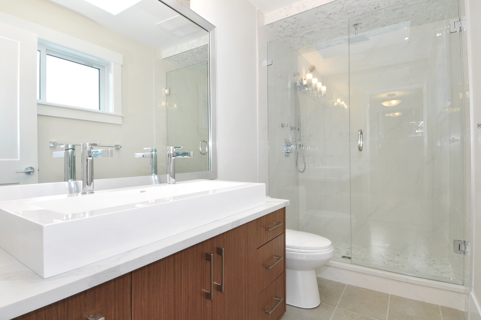 Photo of a mid-sized modern master bathroom in Vancouver with flat-panel cabinets, medium wood cabinets, an alcove shower, a two-piece toilet, white tile, white walls, ceramic floors, a trough sink, engineered quartz benchtops, beige floor, a hinged shower door and white benchtops.