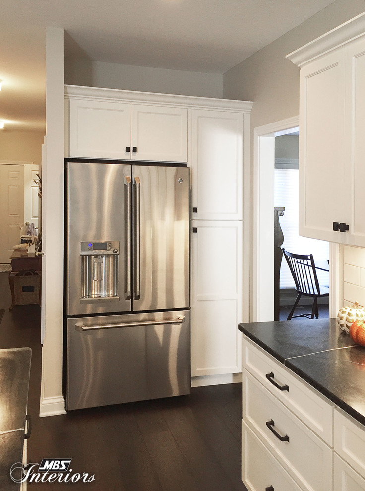 Mid-sized transitional u-shaped dark wood floor and brown floor eat-in kitchen photo with an undermount sink, recessed-panel cabinets, white cabinets, soapstone countertops, white backsplash, subway tile backsplash, stainless steel appliances and an island