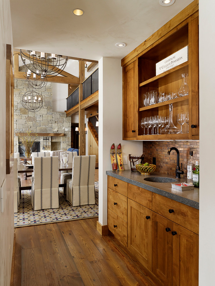 This is an example of a country single-wall home bar in Other with an undermount sink, medium wood cabinets, medium hardwood floors and shaker cabinets.