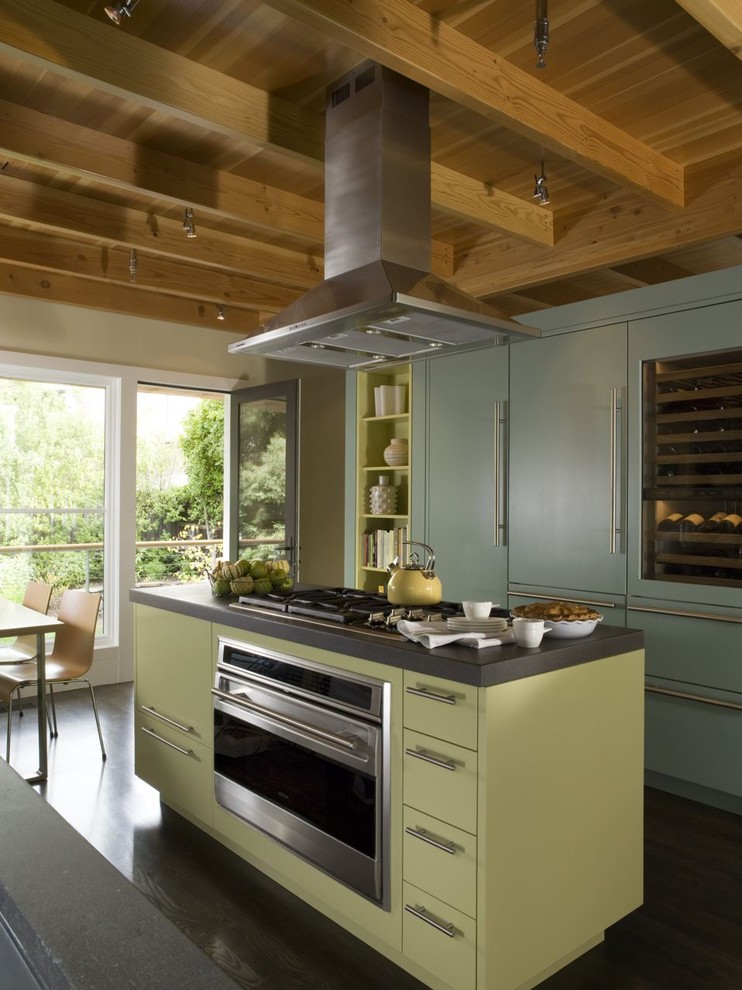 Mid-sized eclectic l-shaped open plan kitchen in San Francisco with green cabinets, panelled appliances, dark hardwood floors, with island, an undermount sink, open cabinets and black splashback.