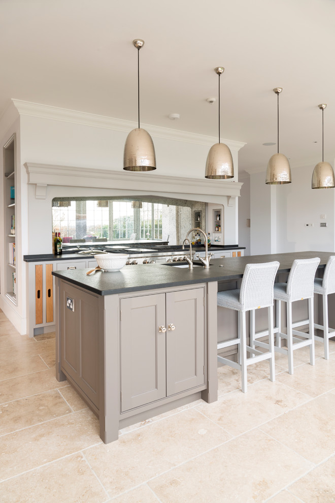 Expansive transitional single-wall open plan kitchen in Essex with a farmhouse sink, flat-panel cabinets, grey cabinets, quartzite benchtops, metallic splashback, mirror splashback, stainless steel appliances, limestone floors and with island.