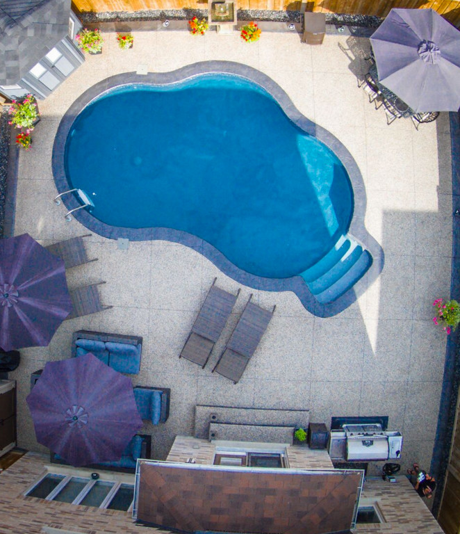 Design ideas for a small transitional backyard kidney-shaped pool in Toronto with stamped concrete.