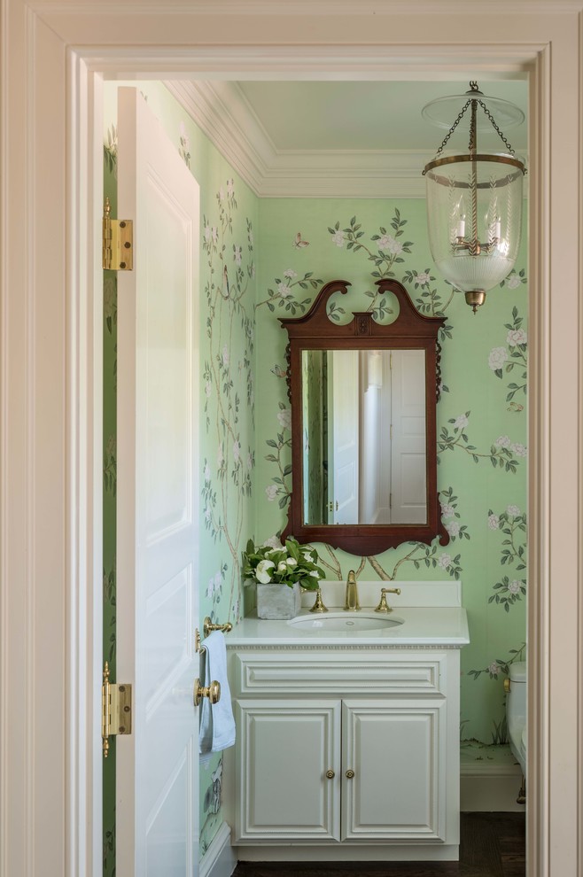 This is an example of a small traditional powder room in Boston with raised-panel cabinets, white cabinets, a one-piece toilet, green walls, medium hardwood floors, an undermount sink, marble benchtops, brown floor and white benchtops.