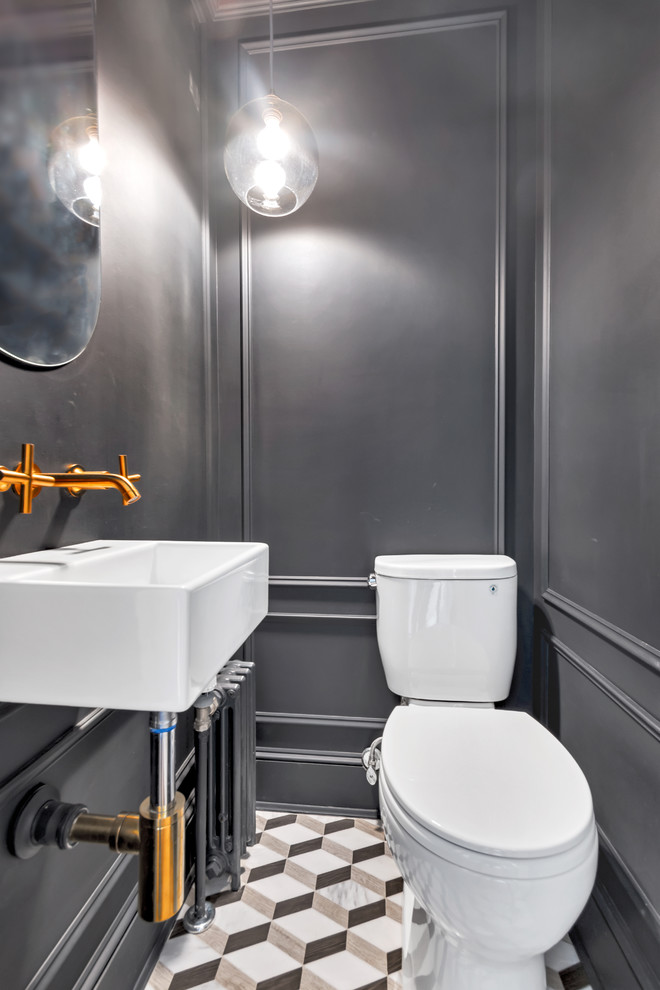 Small industrial powder room in New York with a two-piece toilet, ceramic floors and a wall-mount sink.