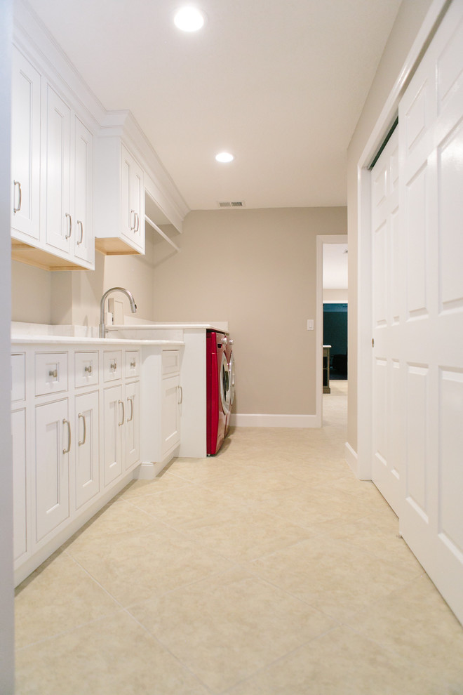This is an example of a mid-sized traditional galley dedicated laundry room in Orlando with an undermount sink, recessed-panel cabinets, white cabinets, quartz benchtops, grey walls, porcelain floors and a side-by-side washer and dryer.