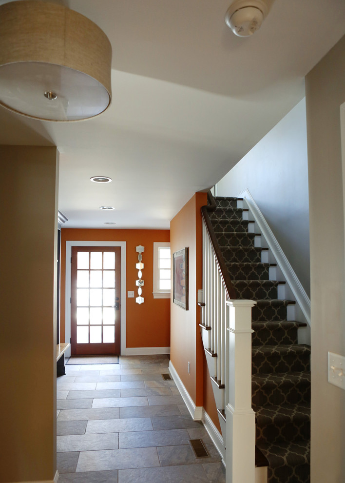 This is an example of a mid-sized traditional foyer in New York with orange walls, slate floors, a single front door and a dark wood front door.