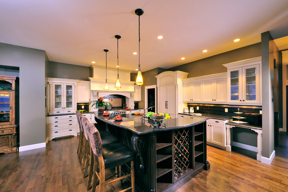 Eat-in kitchen - traditional l-shaped eat-in kitchen idea in Other with an undermount sink, raised-panel cabinets, white cabinets, granite countertops, brown backsplash, subway tile backsplash and stainless steel appliances