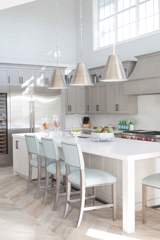 Design ideas for a beach style l-shaped kitchen in Miami with an undermount sink, shaker cabinets, grey cabinets, white splashback, stainless steel appliances, with island, beige floor and white benchtop.