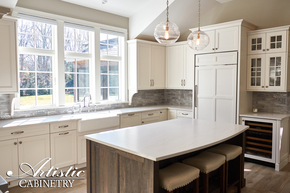 Open concept kitchen - mid-sized transitional u-shaped porcelain tile and beige floor open concept kitchen idea in New York with a farmhouse sink, shaker cabinets, white cabinets, quartzite countertops, gray backsplash, porcelain backsplash, stainless steel appliances, an island and gray countertops