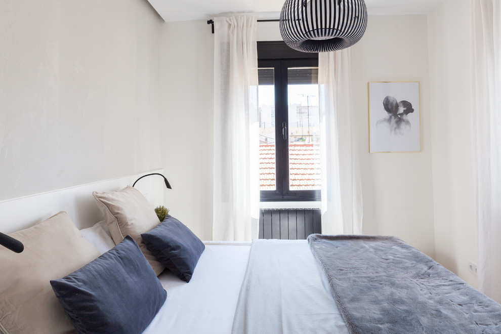Mid-sized scandinavian master bedroom in Madrid with white walls, laminate floors, no fireplace and brown floor.