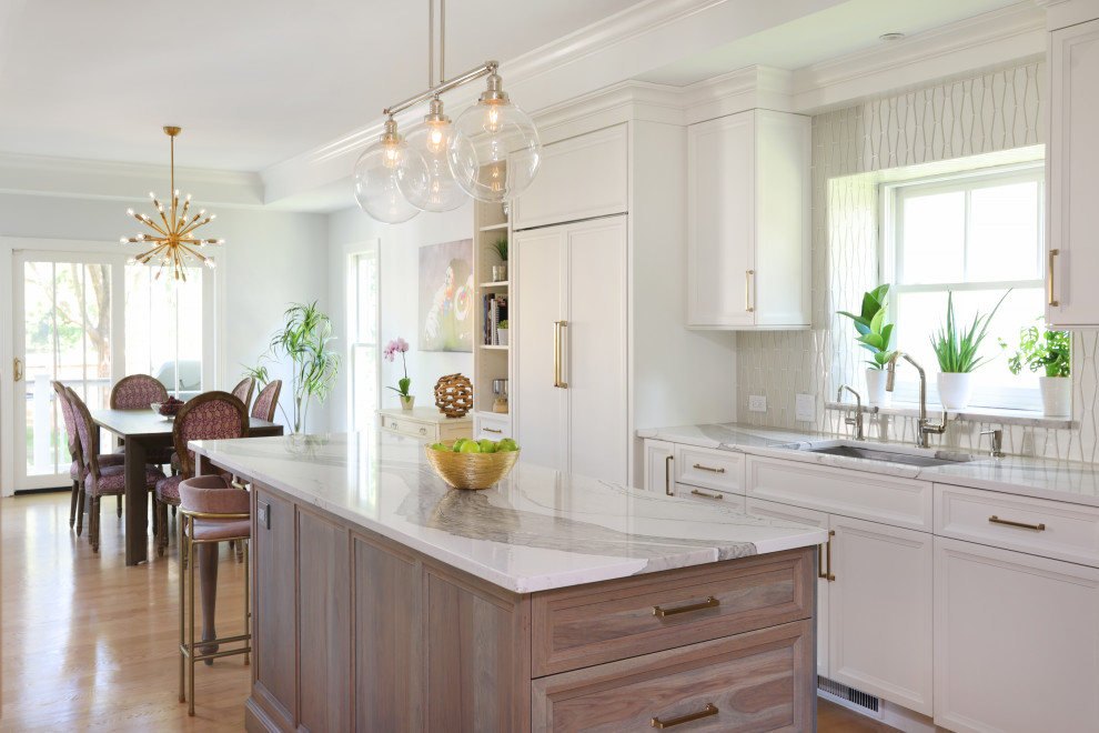 Inspiration for a large transitional u-shaped light wood floor and tray ceiling eat-in kitchen remodel in Chicago with a single-bowl sink, flat-panel cabinets, white cabinets, quartz countertops, white backsplash, glass tile backsplash, paneled appliances, an island and white countertops