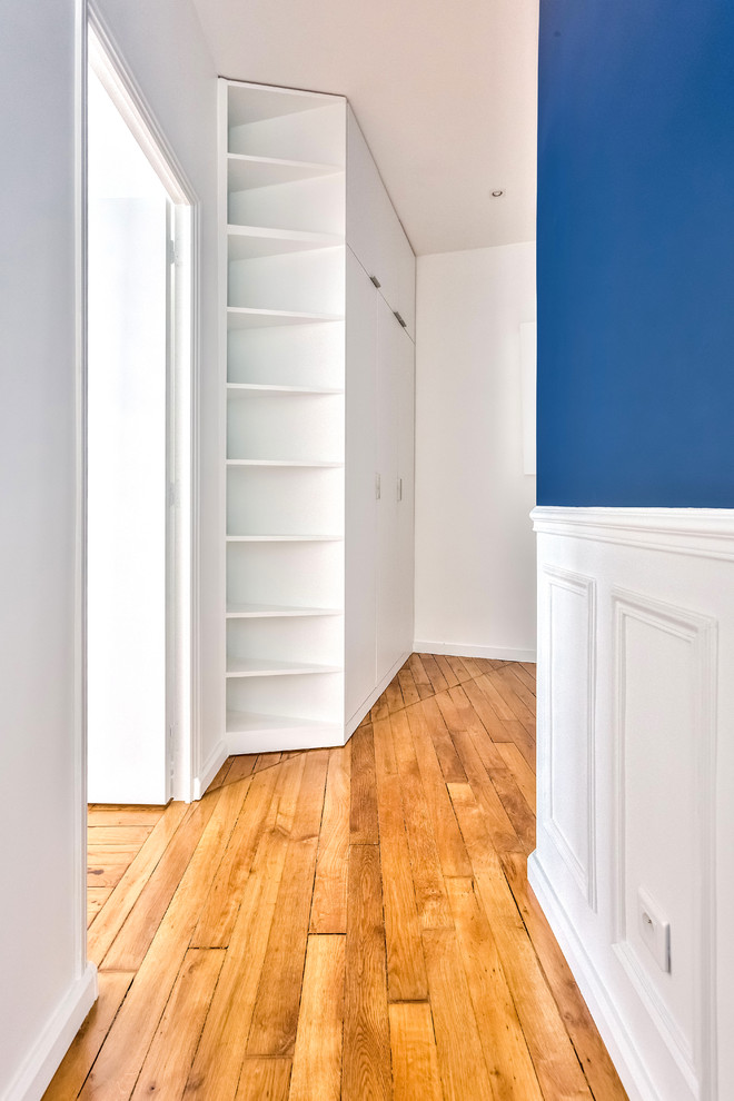 This is an example of a large traditional hallway in Paris with blue walls, medium hardwood floors and brown floor.