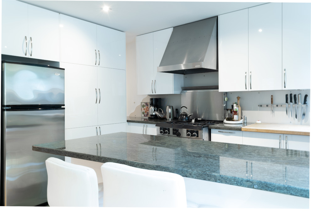 Inspiration for a mid-sized modern l-shaped open plan kitchen in Toronto with an undermount sink, flat-panel cabinets, white cabinets, granite benchtops, grey splashback, metal splashback, stainless steel appliances, ceramic floors, a peninsula, green floor and green benchtop.