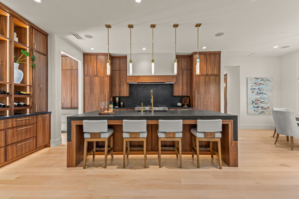 Inspiration for a contemporary l-shaped light wood floor and beige floor open concept kitchen remodel in Dallas with an undermount sink, dark wood cabinets, black backsplash, stone slab backsplash, paneled appliances, an island and black countertops