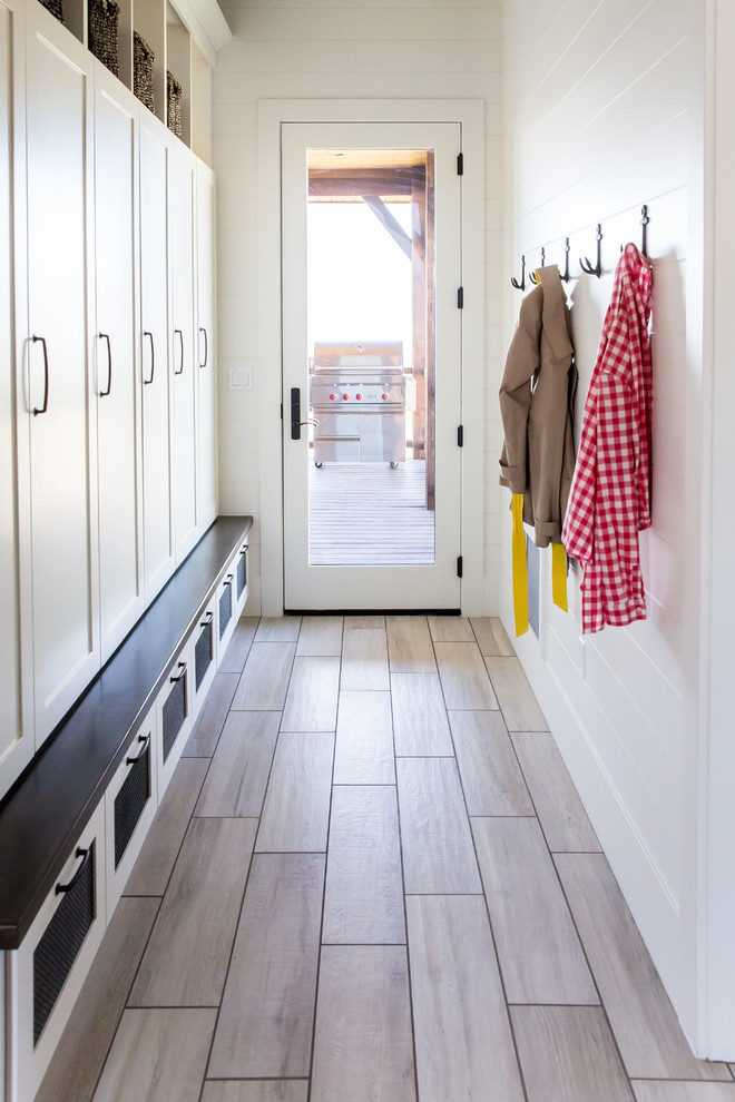Photo of a large country mudroom in Salt Lake City with white walls, porcelain floors, a single front door and a glass front door.