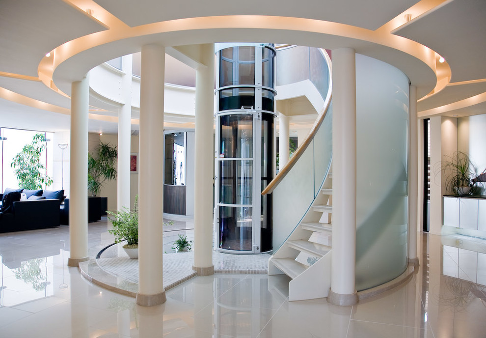 This is an example of a large contemporary acrylic curved staircase in Vancouver with open risers and glass railing.