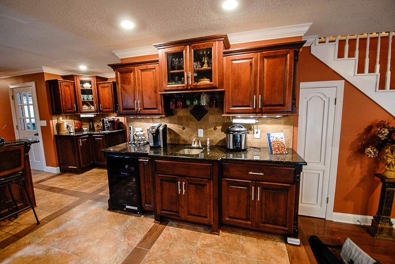 Photo of a traditional kitchen in Other with an undermount sink, raised-panel cabinets, dark wood cabinets, granite benchtops, beige splashback, stone tile splashback, stainless steel appliances and with island.