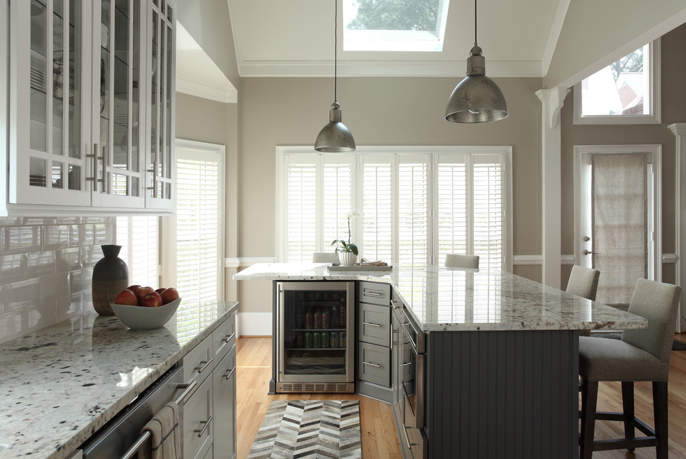 Mid-sized transitional l-shaped light wood floor and beige floor enclosed kitchen photo with shaker cabinets, gray cabinets, granite countertops, white backsplash, porcelain backsplash, stainless steel appliances and an island