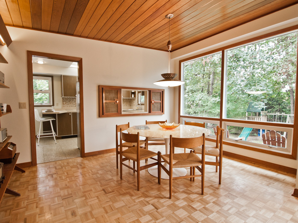 This is an example of a midcentury dining room in Portland with white walls and medium hardwood floors.