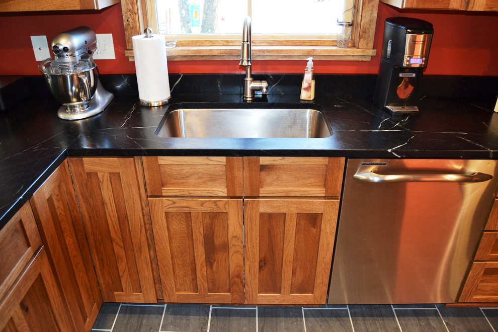 Eat-in kitchen - mid-sized rustic l-shaped slate floor eat-in kitchen idea in Burlington with an undermount sink, shaker cabinets, distressed cabinets, soapstone countertops, stainless steel appliances and a peninsula