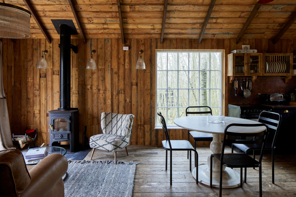 Immagine di una sala da pranzo stile rurale con pareti marroni, pavimento in legno massello medio, pavimento marrone, travi a vista e soffitto a volta
