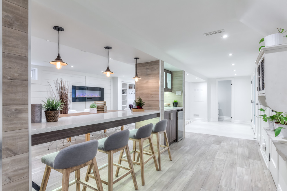 Large beach style galley seated home bar in Toronto with laminate floors, an undermount sink, shaker cabinets, dark wood cabinets and quartzite benchtops.