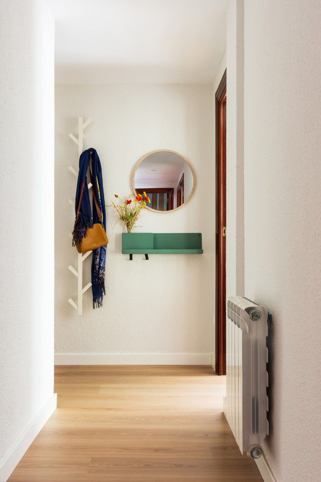 Foto på en liten minimalistisk ingång och ytterdörr, med vita väggar, mellanmörkt trägolv och brunt golv