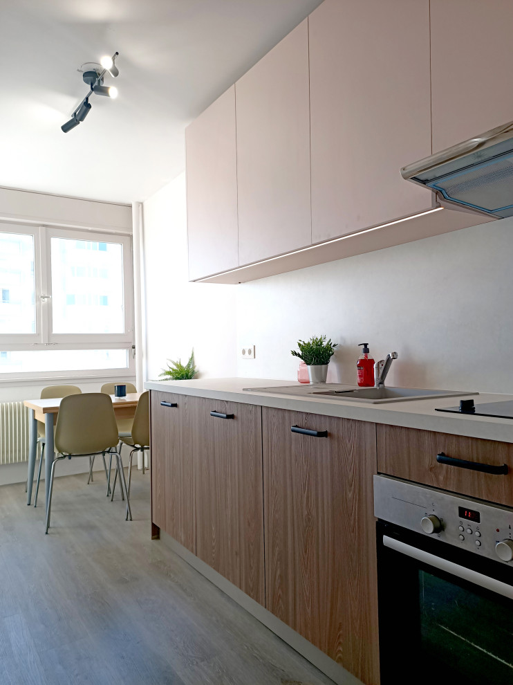 Idéer för avskilda, små funkis linjära grått kök, med en enkel diskho, släta luckor, skåp i mellenmörkt trä, bänkskiva i betong, grått stänkskydd, integrerade vitvaror och mellanmörkt trägolv