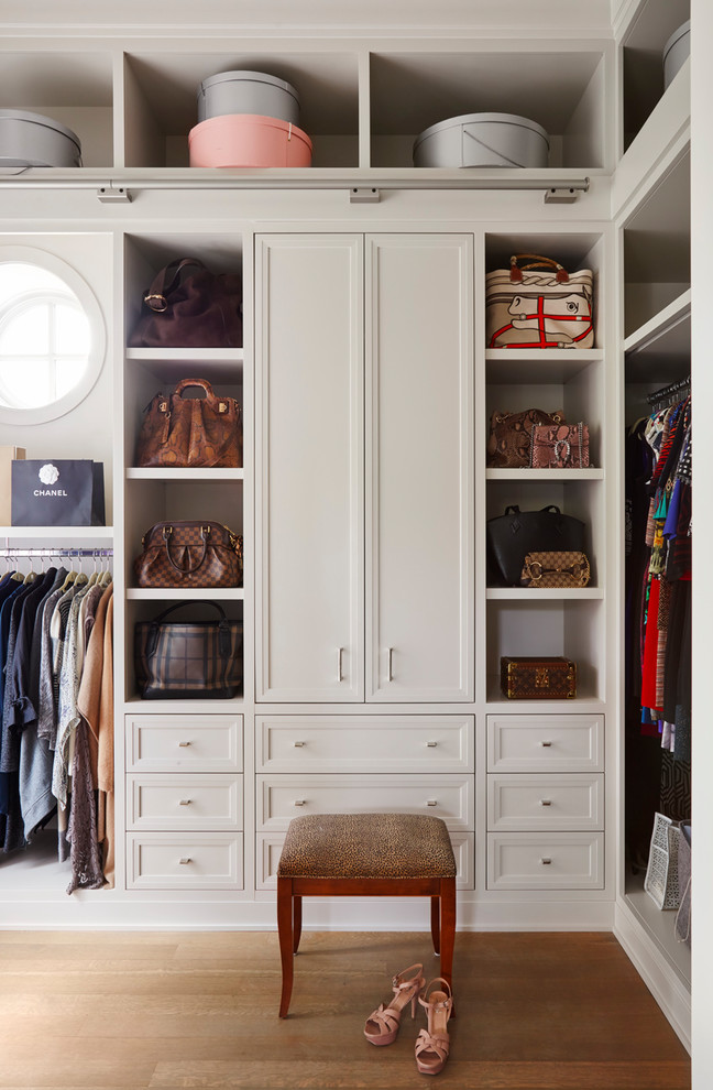 This is an example of a transitional women's walk-in wardrobe in Chicago with recessed-panel cabinets, beige cabinets and medium hardwood floors.