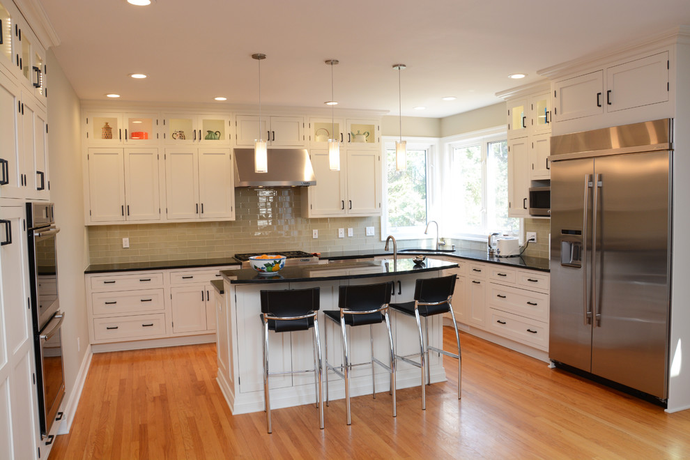 This is an example of a large transitional u-shaped eat-in kitchen in Baltimore with a double-bowl sink, shaker cabinets, white cabinets, granite benchtops, glass tile splashback, stainless steel appliances, light hardwood floors and with island.