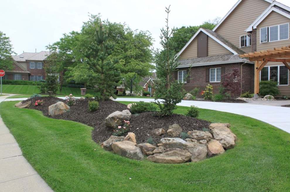 Photo of a large traditional front yard full sun driveway for spring in Omaha with mulch.