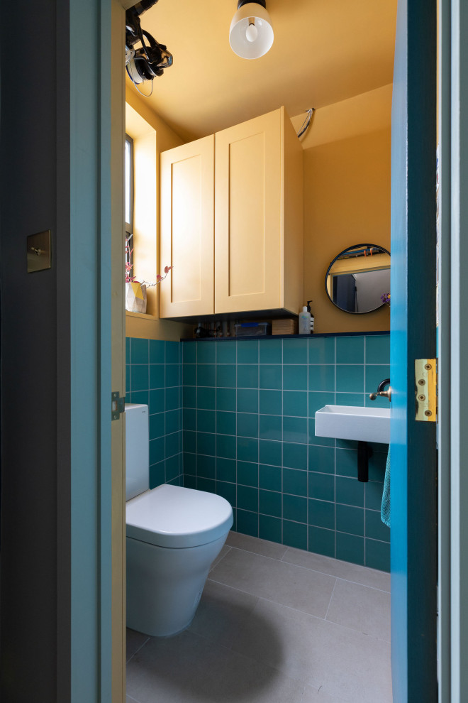 Cette image montre une petite salle de bain avec un carrelage vert, des carreaux de céramique, un mur jaune, un lavabo suspendu et meuble simple vasque.