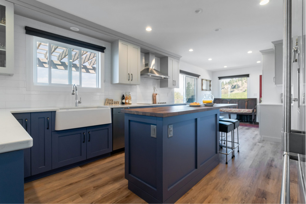 Eat-in kitchen - mid-sized transitional u-shaped medium tone wood floor and brown floor eat-in kitchen idea with recessed-panel cabinets, gray cabinets, quartz countertops, white backsplash, ceramic backsplash, stainless steel appliances, an island and white countertops