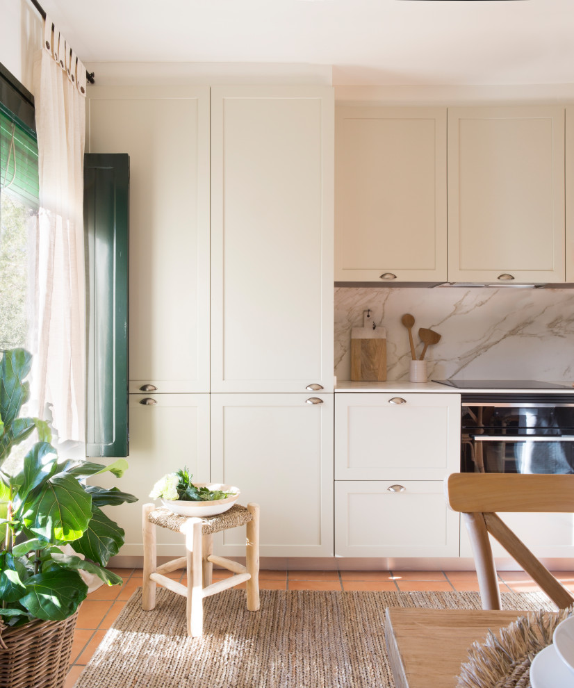 Bild på ett lantligt kök, med en enkel diskho, luckor med profilerade fronter, vita skåp, vitt stänkskydd, stänkskydd i travertin, klinkergolv i terrakotta och brunt golv