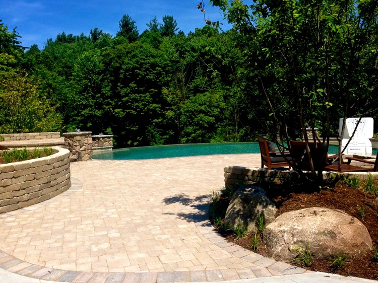 Inspiration for a large transitional backyard custom-shaped infinity pool in Grand Rapids with a water feature and natural stone pavers.