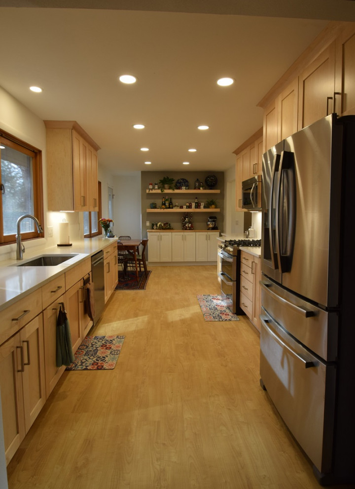 Kitchen - galley vinyl floor kitchen idea with an undermount sink, shaker cabinets, light wood cabinets, quartz countertops, stainless steel appliances and white countertops