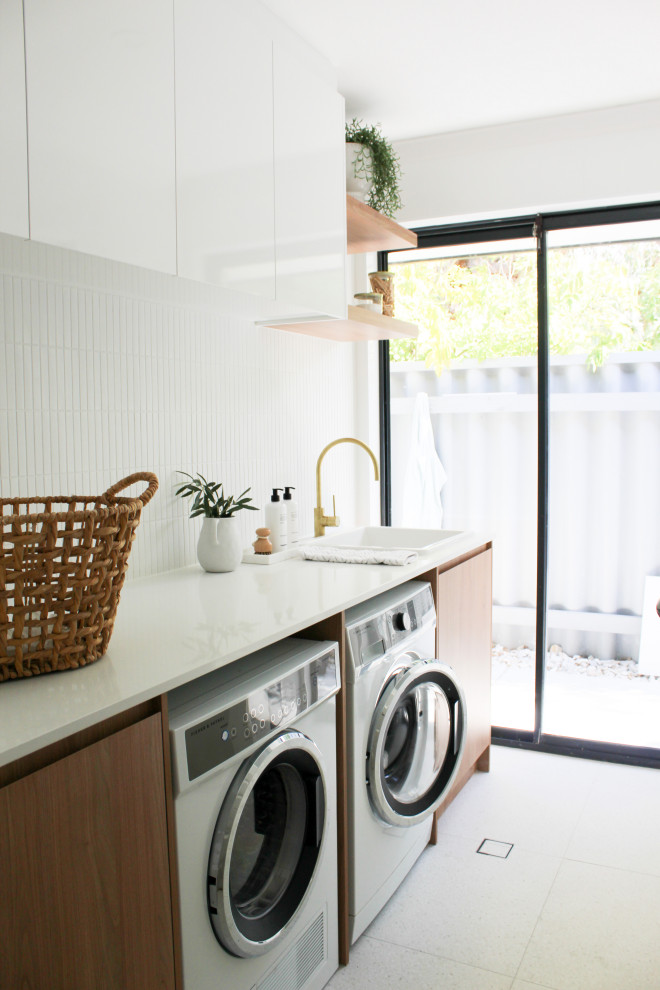 Inspiration for a mid-sized country single-wall dedicated laundry room in Perth with a farmhouse sink, flat-panel cabinets, dark wood cabinets, quartz benchtops, white walls, porcelain floors, a side-by-side washer and dryer, multi-coloured floor and white benchtop.