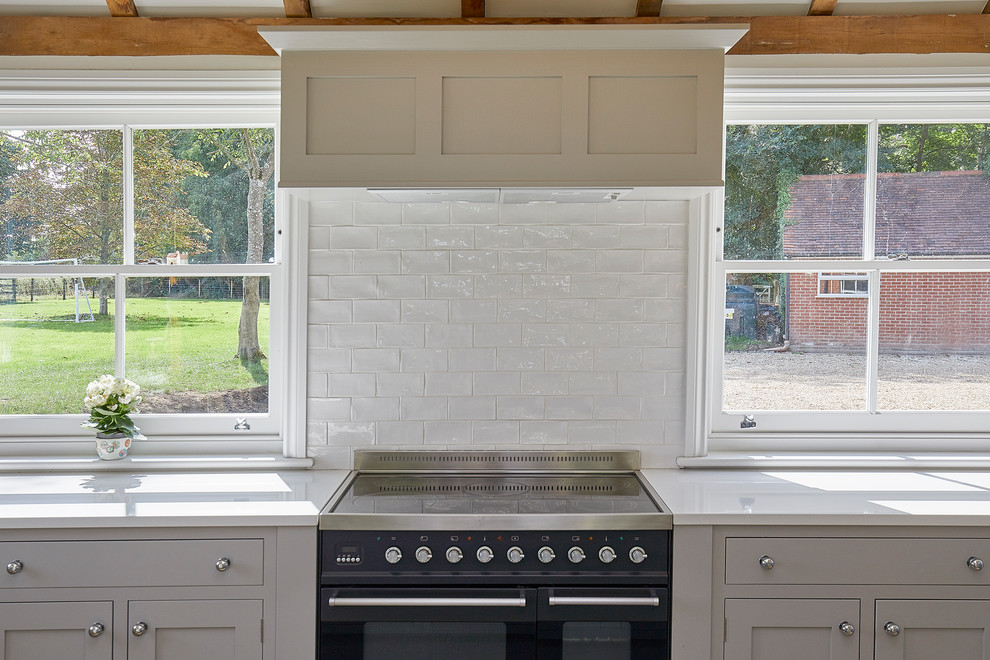 Design ideas for a large u-shaped kitchen/diner in Surrey with a double-bowl sink, shaker cabinets, grey cabinets, composite countertops, white splashback, porcelain splashback, stainless steel appliances, travertine flooring, an island, beige floors and yellow worktops.