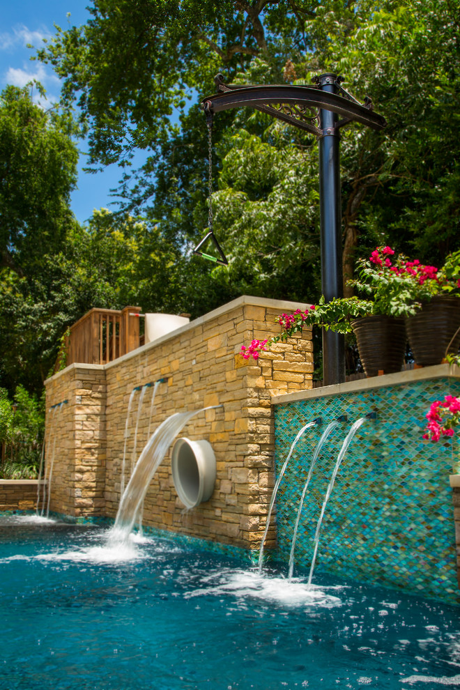 This is an example of a large country side yard rectangular lap pool in Austin with a water slide and natural stone pavers.
