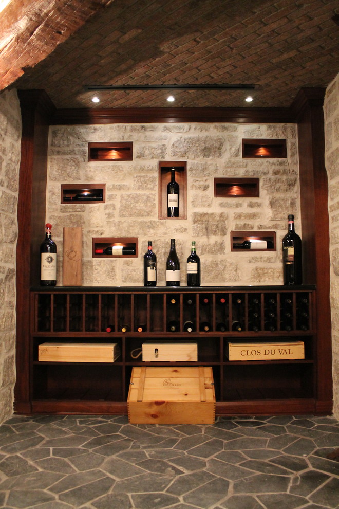 Expansive mediterranean wine cellar in Ottawa with slate floors, display racks and grey floor.