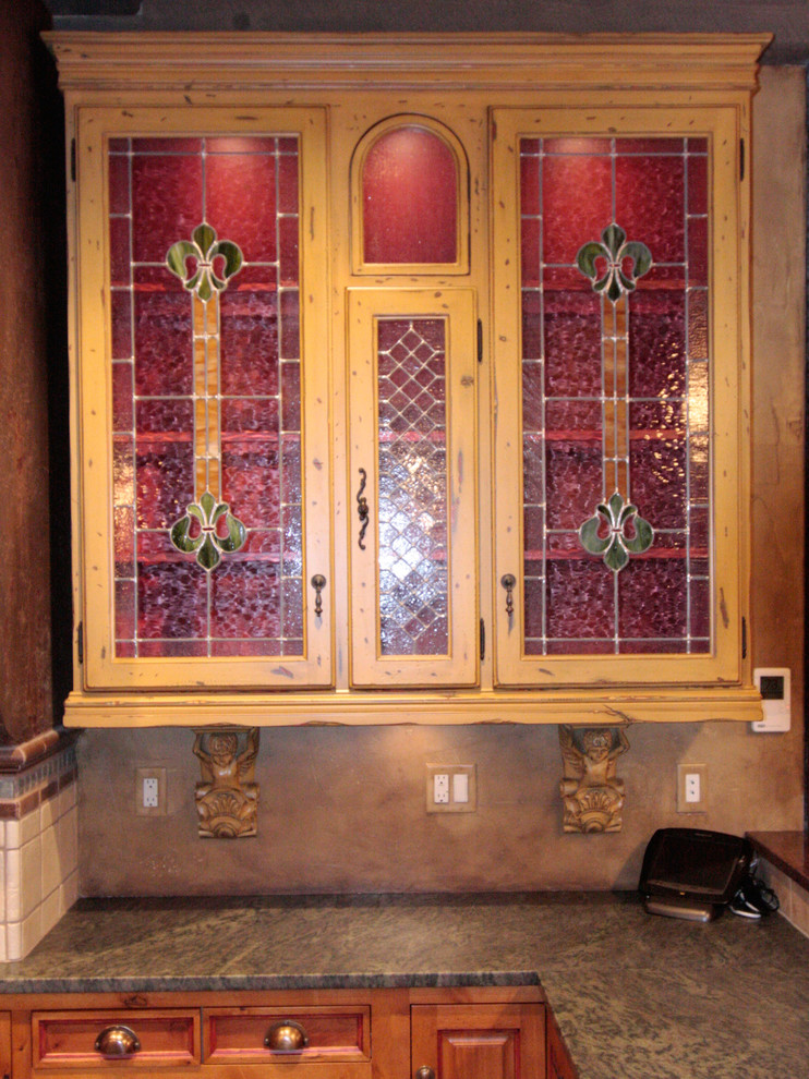 Large eclectic u-shaped slate floor eat-in kitchen photo with a farmhouse sink, raised-panel cabinets, distressed cabinets, granite countertops, terra-cotta backsplash, paneled appliances and an island
