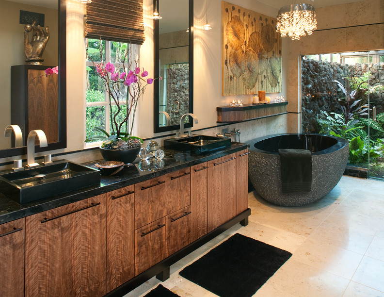 Photo of a mid-sized tropical master bathroom in San Diego with flat-panel cabinets, medium wood cabinets, a japanese tub, an open shower, a one-piece toilet, black tile, stone tile, beige walls, ceramic floors, a vessel sink and solid surface benchtops.