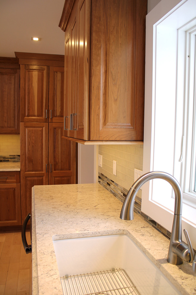 Inspiration for a large transitional u-shaped light wood floor and beige floor open concept kitchen remodel in Boston with an undermount sink, raised-panel cabinets, medium tone wood cabinets, quartz countertops, multicolored backsplash, glass tile backsplash, stainless steel appliances, an island and beige countertops