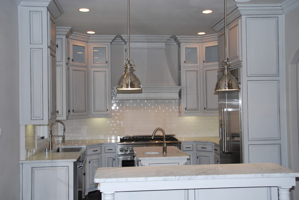 Design ideas for a small traditional u-shaped open plan kitchen in Dallas with a farmhouse sink, raised-panel cabinets, white cabinets, marble benchtops, white splashback, subway tile splashback, stainless steel appliances, medium hardwood floors and multiple islands.