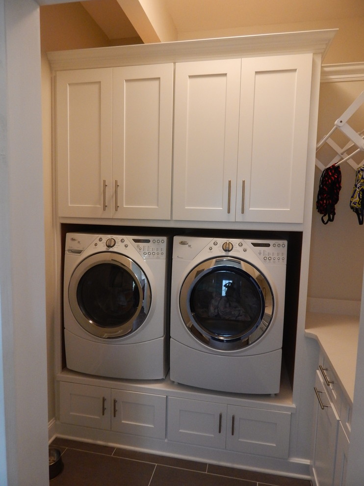 Design ideas for a large traditional l-shaped laundry room in Charlotte with a farmhouse sink, shaker cabinets, white cabinets, granite benchtops, grey splashback, glass tile splashback and dark hardwood floors.
