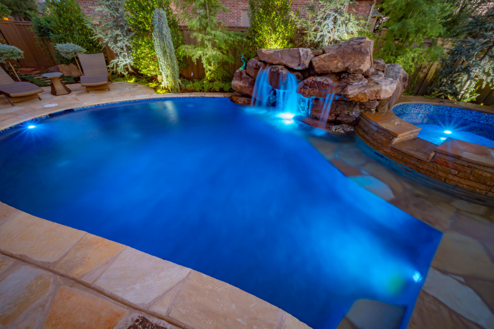 Modelo de piscina natural clásica renovada de tamaño medio a medida en patio trasero con privacidad y adoquines de piedra natural